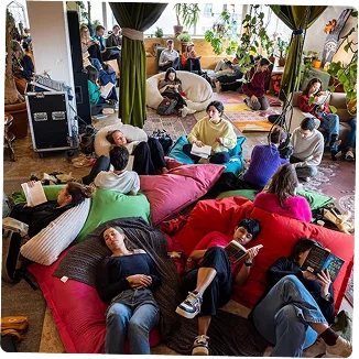 Een groep vrienden die samen ontspant in een woonkamer op banken en kussens.